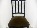 une image représentant une chaise noire dont l'assise est en velours vert