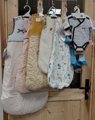 de nombreux vêtements de bébé suspendus à un portant près de la porte