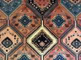 an antique persian rug with a multicolored diamond design