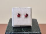 a pair of red garnet stone stud earrings sitting on top of a marble block