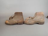 two pairs of brown boots with laces on them sitting on a gray surface