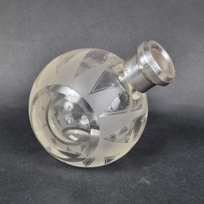 un vase en verre transparent muni d'une poignée argentée sur un fond noir