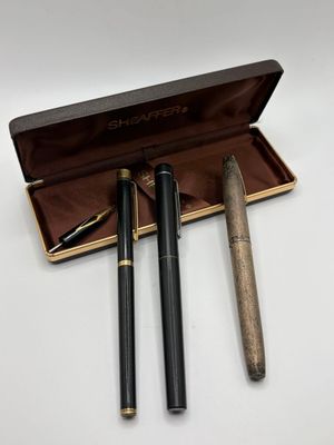 deux stylos dans un étui posé sur une table, à côté d'une paire de lunettes