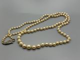 un collier de perles avec un fermoir en argent sur fond gris