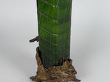 a green vase sitting on top of a tree stump