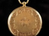 an antique gold pocket watch with a chain on a black background