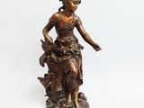 a bronze statue of a woman sitting on top of a rock