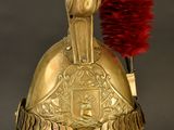 gold helmet with a red feather on top of it on a stand