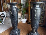 two black vases sitting next to each other on the floor