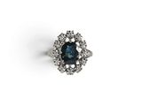 gros plan d'une bague avec une pierre bleue entourée de diamants blancs