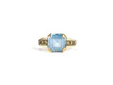 a close up of a ring with a blue topaz stone and diamonds