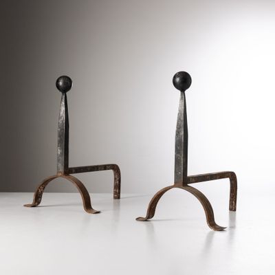 une paire de bougies en fer posées sur une table blanche, sur fond gris