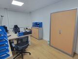 a room with a desk, chairs, and a door