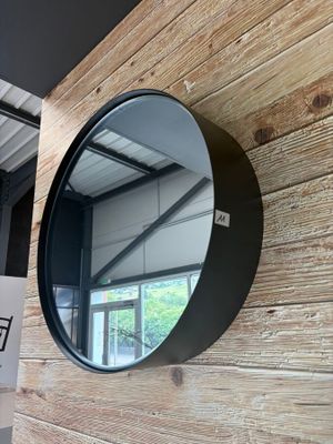 un miroir rond accroché à un mur en bois, à côté d'un panneau