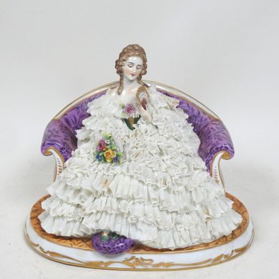 figurine représentant une femme en robe blanche, assise sur une chaise violette