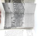 a hand that is holding a book with a picture of a city on it