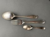 three silver spoons and a fork on a gray surface
