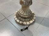une statue représentant une femme, posée sur un socle, au milieu d'un sol carrelé
