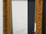 an ornate gold frame with a black background and a white wall