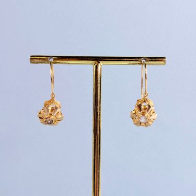 the gold earrings are hanging from a gold stand on a blue background