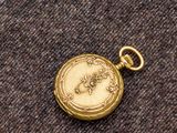 une image représentant une montre de poche en or posée sur un morceau de tissu