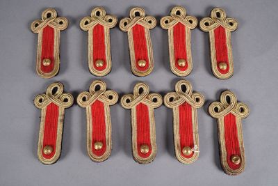 six pairs of red and gold military badges on a gray surface