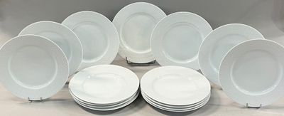 twelve white dinner plates stacked on top of each other on a table