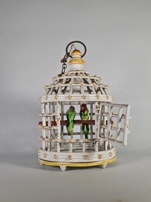 un petit oiseau dans une cage à laquelle est accroché un porte-clés
