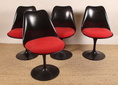 quatre chaises « Tulip » noires avec des coussins rouges et des piètements noirs