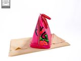 a pink purse with a red handle sitting on top of a piece of paper