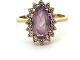gros plan d'une bague avec une pierre violette entourée de diamants