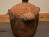 un grand pot marron posé par terre près d'un mur