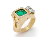 a close up of a ring with a green stone and two diamonds