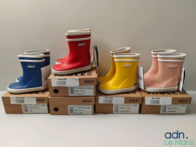 several pairs of children ' s rain boots are lined up on boxes