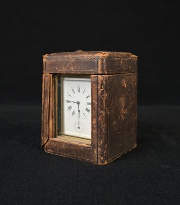 une petite horloge posée sur une surface noire