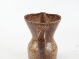 a brown vase that is sitting on a white surface