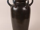 a black vase with two handles sitting on a white surface