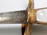 a close up of a knife with a gold handle