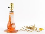 an orange and white glass lamp with a gold metal base and a cord