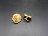 a close up of a pair of gold earrings on a table