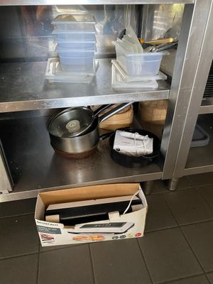 une étagère métallique avec des casseroles et des poêles dans une cuisine