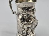 un pichet ancien en argent sur lequel est représenté un homme coiffé d'un chapeau