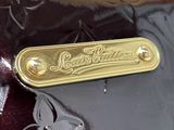 a close up of a shiny black bag with a gold nameplate