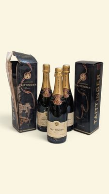 trois bouteilles de champagne et une boîte de chocolats posées sur un plan de travail blanc