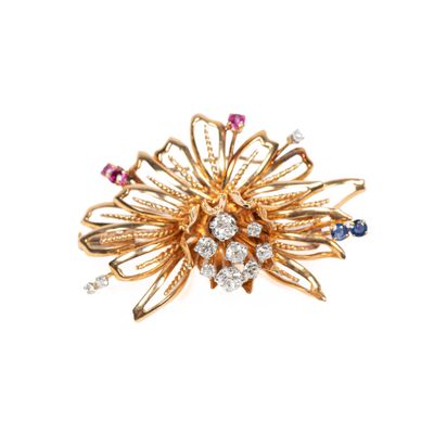 un gros plan sur une broche en or sertie de pierres multicolores