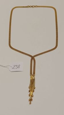 gros plan d'un collier en or sur une surface blanche