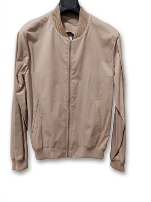 une veste beige suspendue à un cintre sur un mur blanc