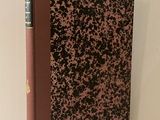 le livre est posé sur une étagère blanche, avec une couverture marron