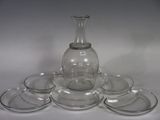 a glass vase and six glasses on a white table