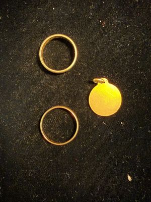 two gold rings and a gold disc on a black surface